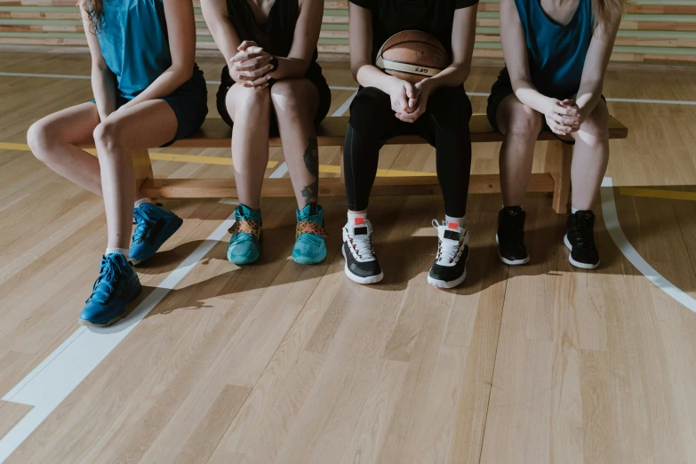 a group of women sitting on top of a wooden bench, by Nina Hamnett, trending on pexels, wearing basketball jersey, sitting on the floor, running shoes, local gym