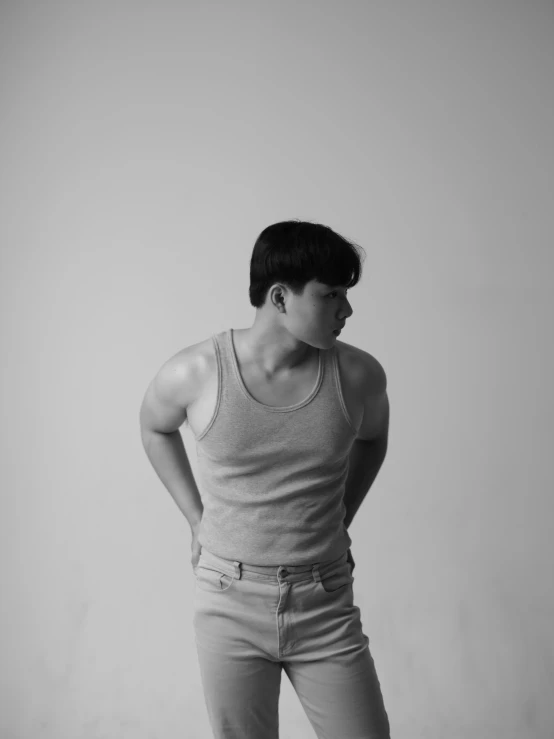 a man in a tank top standing on a skateboard, a black and white photo, inspired by Russell Dongjun Lu, in white room, androgynous person, portrait of a muscular, a muscular