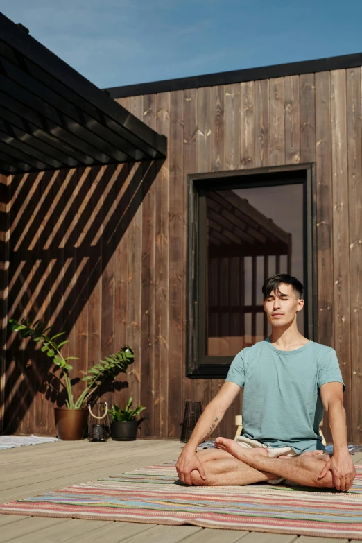 a man sitting in the middle of a yoga pose, a portrait, unsplash, stood outside a wooden cabin, gemma chen, dwell, tv still