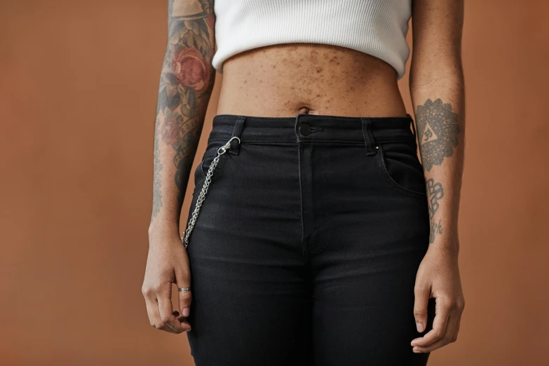 a woman wearing a white top and black pants, a tattoo, trending on pexels, stomach skin, mid 2 0's female, large chain, freckles