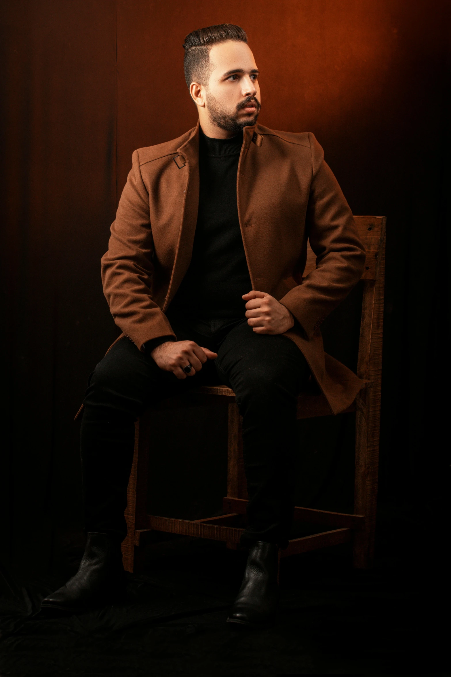 a man sitting on top of a wooden chair, a character portrait, inspired by Yousuf Karsh, pexels, light brown coat, brown:-2, mohamed chahin, portrait of a handsome