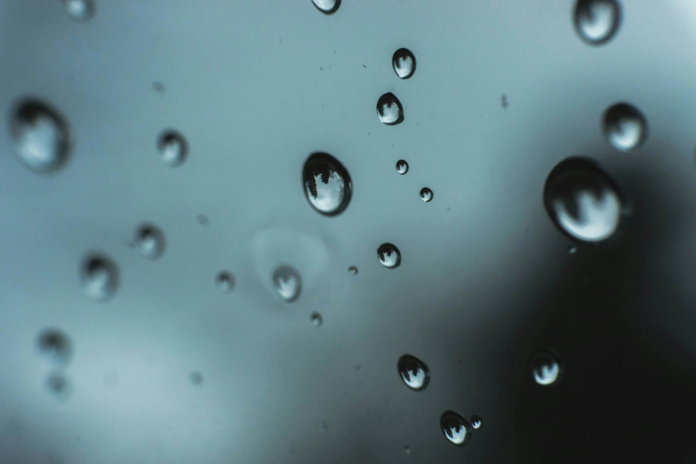 a close up of water droplets on a window, by Ryan Pancoast, trending on unsplash, hyperrealism, desaturated blue, today\'s featured photograph 4k, black-water-background, floating molecules