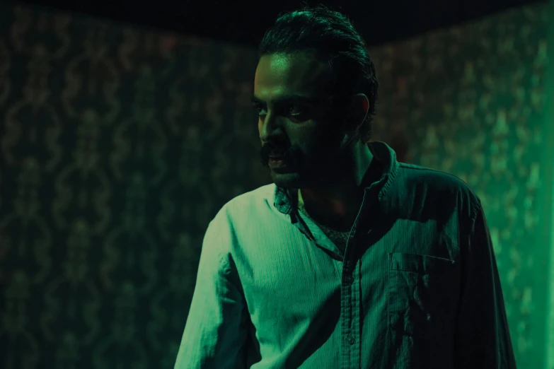 a man standing in a dimly lit room, alejandro, saturation, dynamic movie still, vinayak