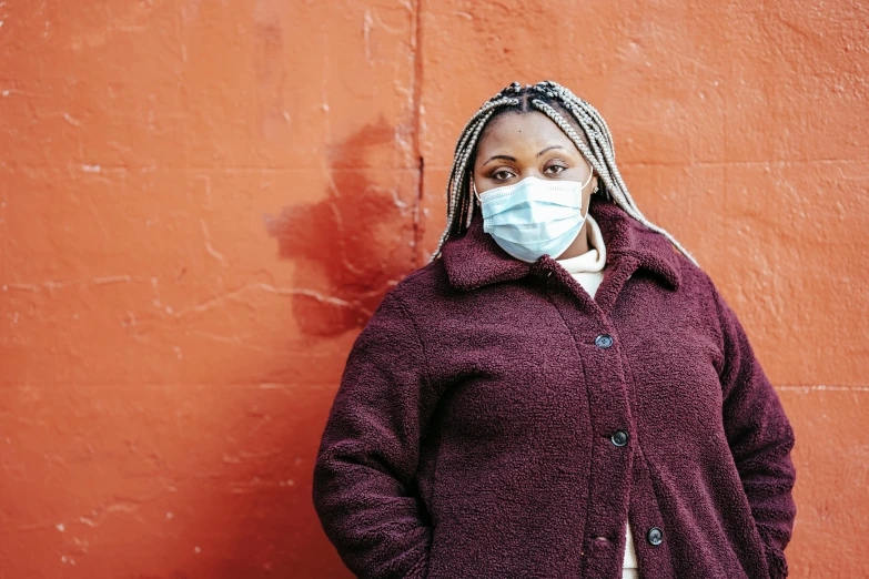 a woman standing in front of a red wall wearing a face mask, hurufiyya, brown, healthcare worker, gritty distopian, gray