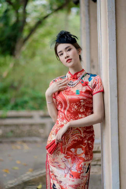 a woman in a red dress leaning against a wall, inspired by Dai Xi, pexels contest winner, cloisonnism, wearing 1890s era clothes, square, 21 years old, attractive and good looking