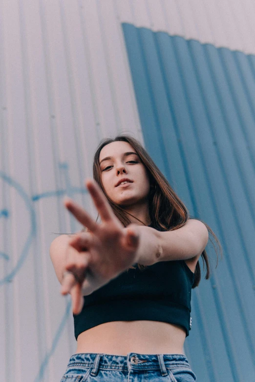 a woman standing in front of a blue wall, pexels contest winner, graffiti, middle finger, dilraba dilmurat, concert photo, blurry