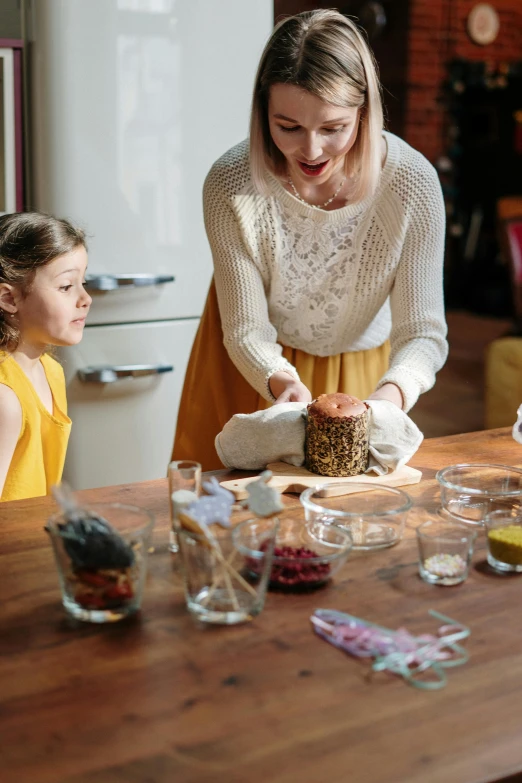 a woman and two young girls sitting at a table, pexels, ingredients on the table, manuka, carving, gif