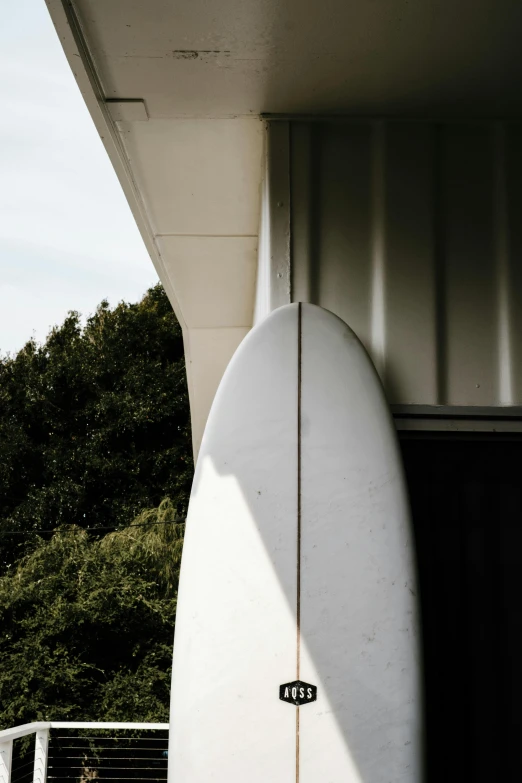 a white surfboard leaning up against a building, unsplash, modernism, high detail photograph, large tail, lush surroundings, nanae kawahara