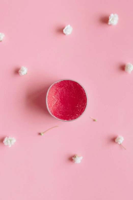 a cup of red liquid surrounded by small white flowers on a pink background, by Will Ellis, trending on pexels, made of candy, cinema still, natural lips, coxcomb