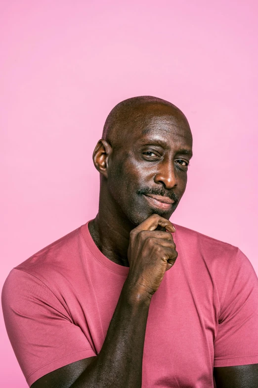 a man in a pink shirt posing for a picture, an album cover, inspired by George Bain, pexels contest winner, lance reddick, plain background, pensive, taejune kim