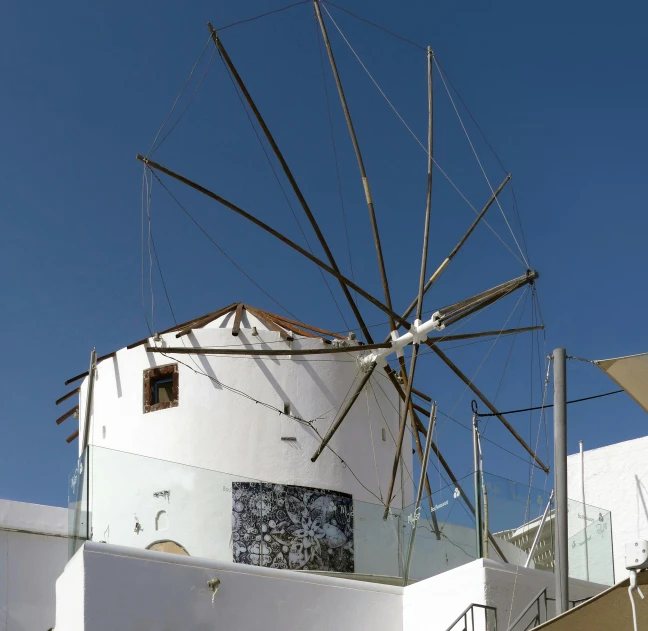 a windmill sitting on top of a white building, capirote, ixions wheel, white gallery, no cropping