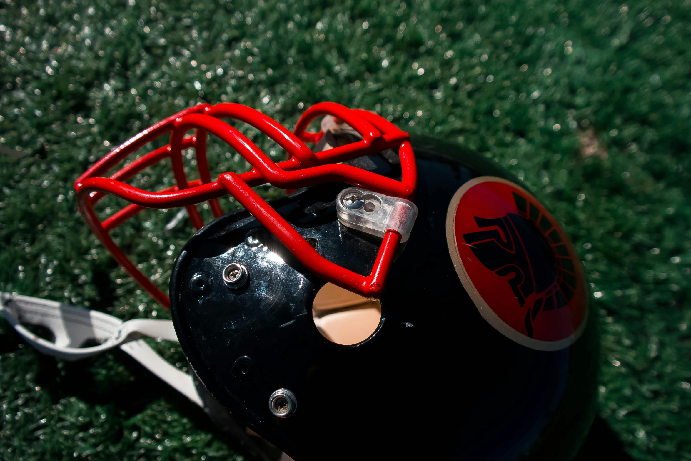 a helmet sitting on top of a lush green field, red and black, mowhawk, suns, photograph credit: ap