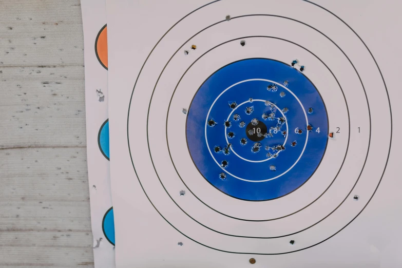 a blue and white target with bullet holes on it, pexels, on a wooden table, various sizes, full colour, birds eye