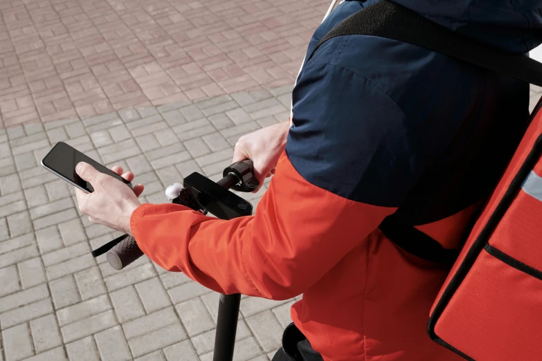 a person on a scooter using a cell phone, inspired by Peter de Sève, unsplash, carrying survival gear, high angle close up shot, future inflatable jacket, dark blue + dark orange