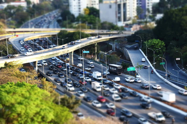 a highway filled with lots of traffic next to tall buildings, a tilt shift photo, by Alejandro Obregón, flickr, instagram post, overpass, ilustration, avatar image