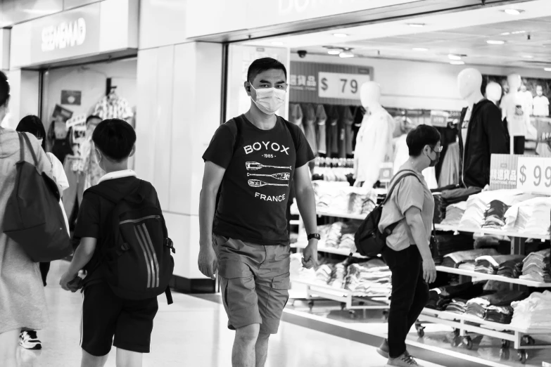 a black and white photo of people in a store, a black and white photo, pexels, happening, asian man, wearing facemask, wearing a t-shirt, man walking