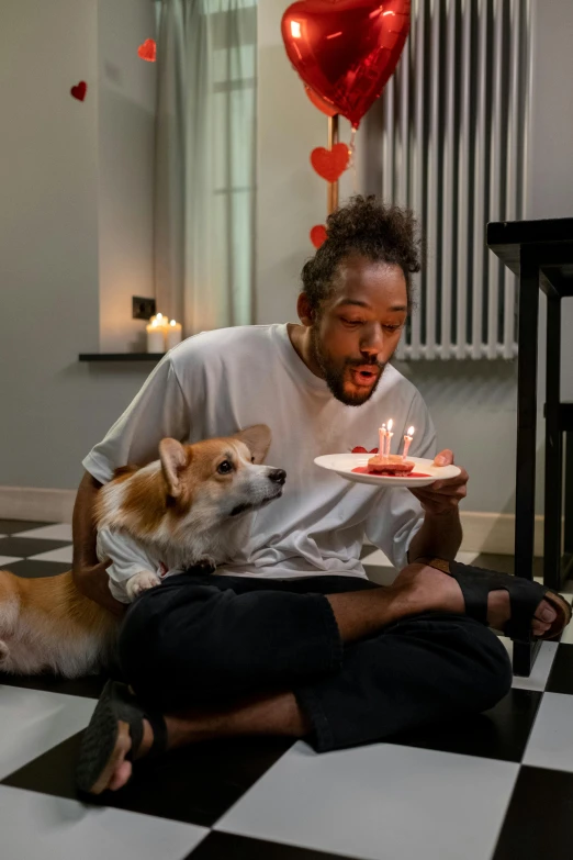 a man sitting on the floor with a dog and a birthday cake, by Adriaen Hanneman, pexels contest winner, hearts, 🐿🍸🍋, : kendrick lamar, fine dining