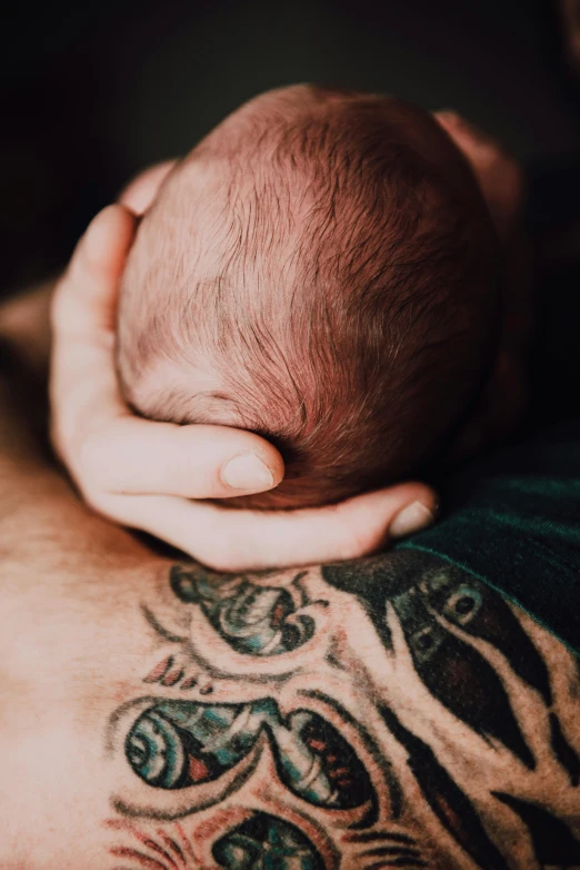 a close up of a person holding a baby, a tattoo, trending on pexels, symbolism, dad bod, asleep, full colour, born survivor