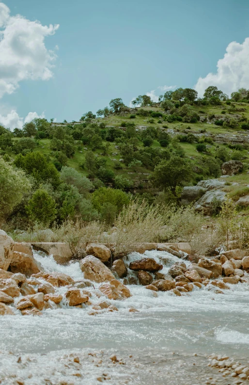 a man standing on top of a rock next to a river, bushveld background, rushing water, cyprus, slide show