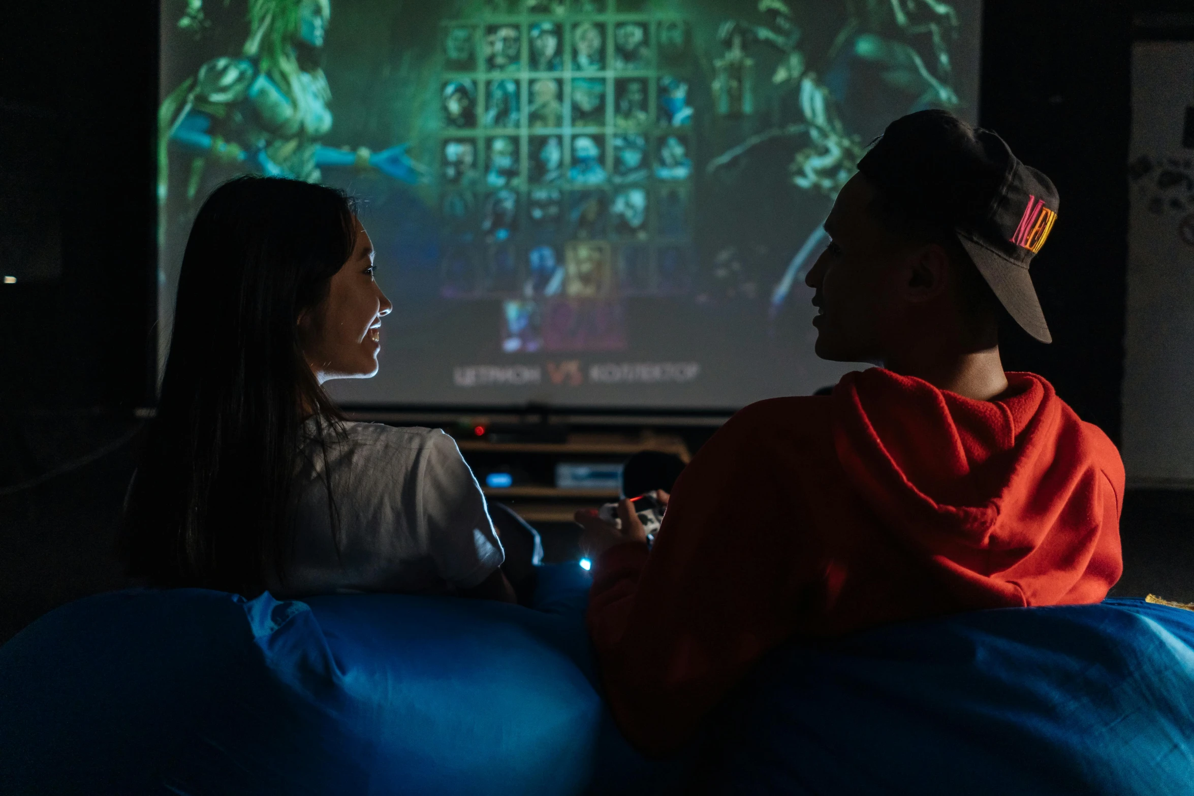 two people sitting on bean bags watching a movie, a portrait, unsplash contest winner, interactive art, fighting game, gamer screen on metallic desk, bisexual lighting, mortal kombat