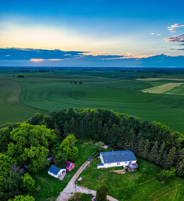 a house sitting on top of a lush green field, by Robert Storm Petersen, pexels contest winner, wide view of a farm, summer evening, wide high angle view, prairie