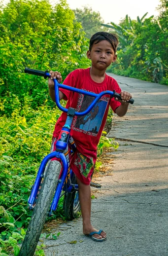 a little boy that is standing next to a bike, by Sven Erixson, pexels contest winner, philippines, young male with walking stick, slide show, colorful picture