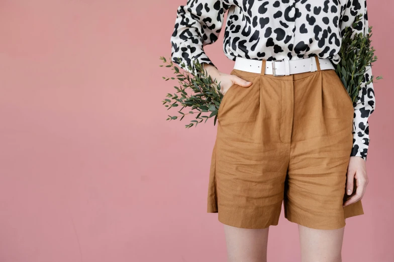 a woman standing in front of a pink wall, inspired by Esaias Boursse, trending on pexels, tan shorts, botanical herbarium paper, wearing a brown, wearing honey