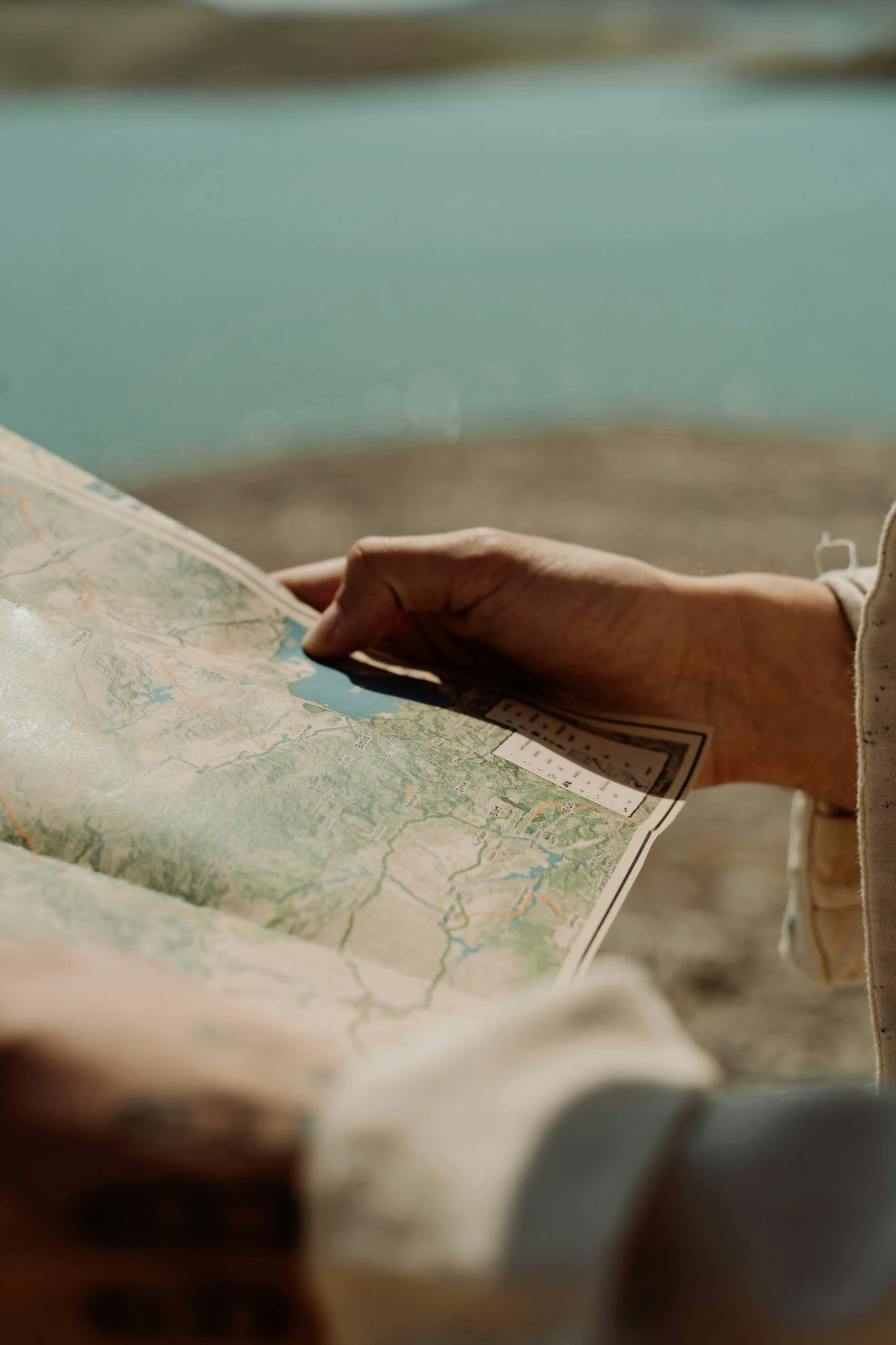 a person holding a map with a lake in the background, by Matija Jama, trending on unsplash, 🤠 using a 🖥, colonial exploration, 'wherever you go, [ cinematic