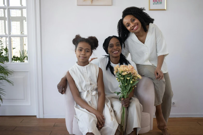 a woman and two young girls posing for a picture, a picture, by Lily Delissa Joseph, pexels contest winner, renaissance, sitting with flowers, young black woman, in white room, husband wife and son