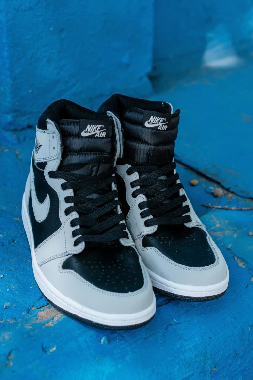 a pair of black and white sneakers on a blue surface, inspired by Jordan Grimmer, unsplash, photorealism, air jordan 1 high, grey and silver, game ready, high angle vertical