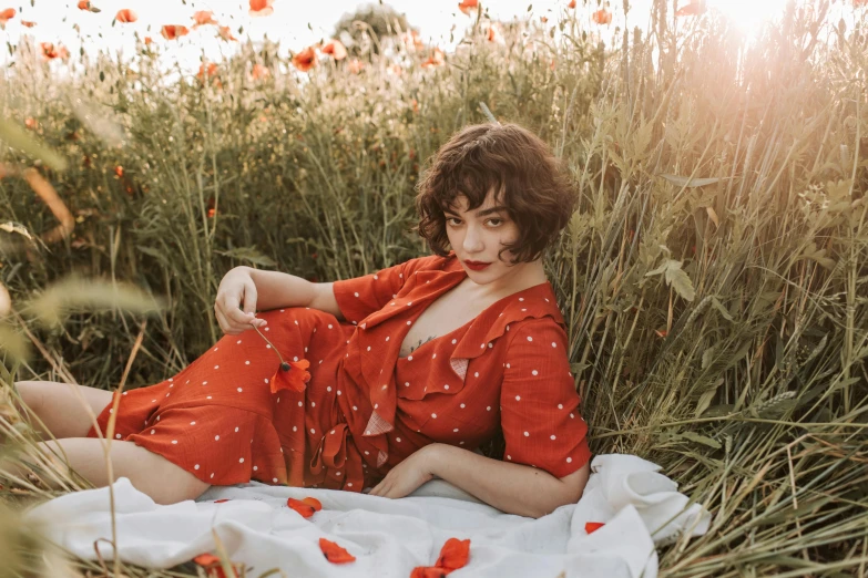 a woman sitting in a field of tall grass, an album cover, by Emma Andijewska, pexels contest winner, red floral dress, wearing an orange jumpsuit, polka dot, milla jovovich