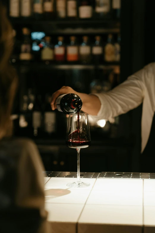 a bartender pours a glass of red wine, pexels contest winner, night time, understated, over the shoulder, sydney hanson