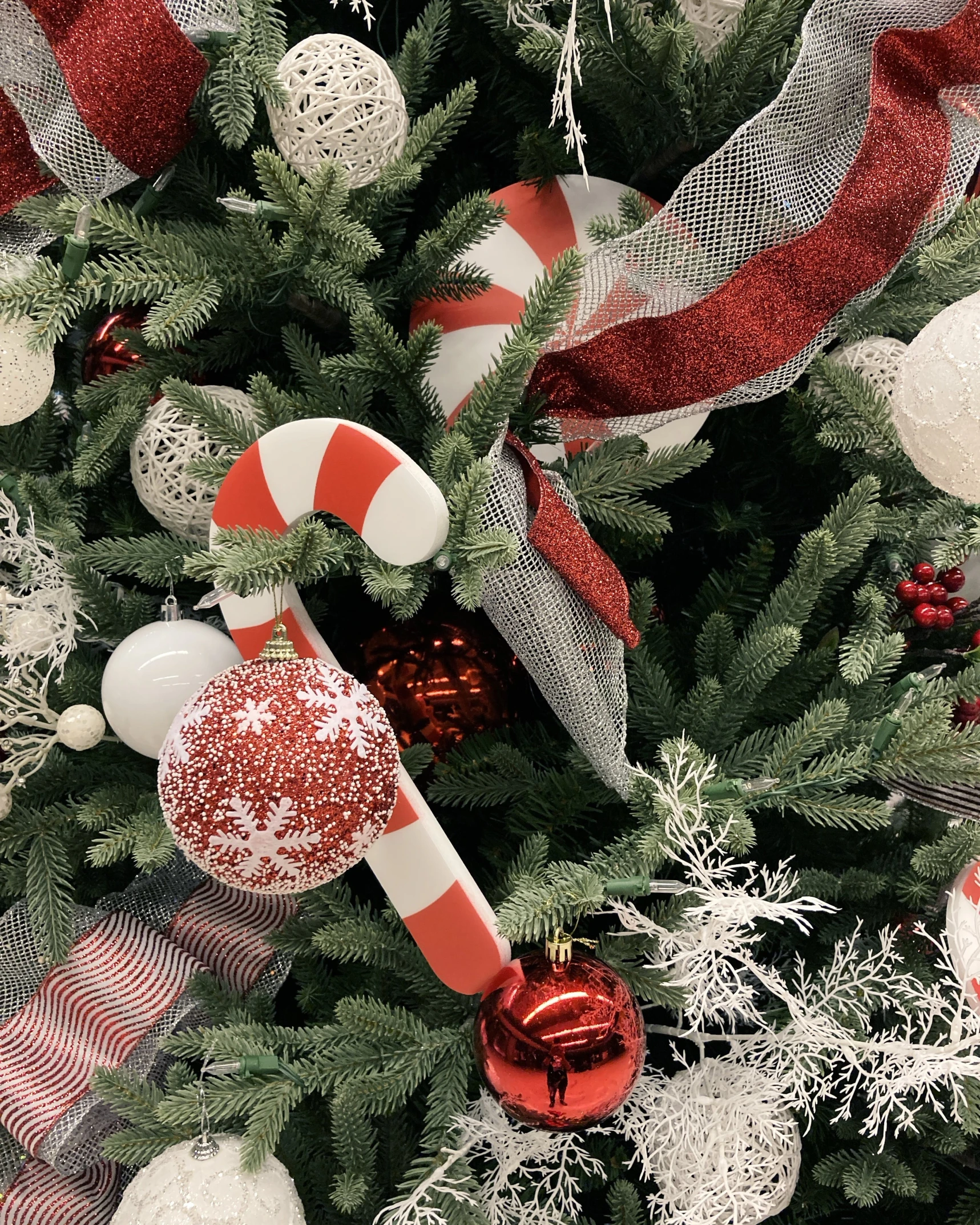 a close up of a christmas tree with ornaments, candy canes, payne's grey and venetian red, 2019 trending photo, multiple stories