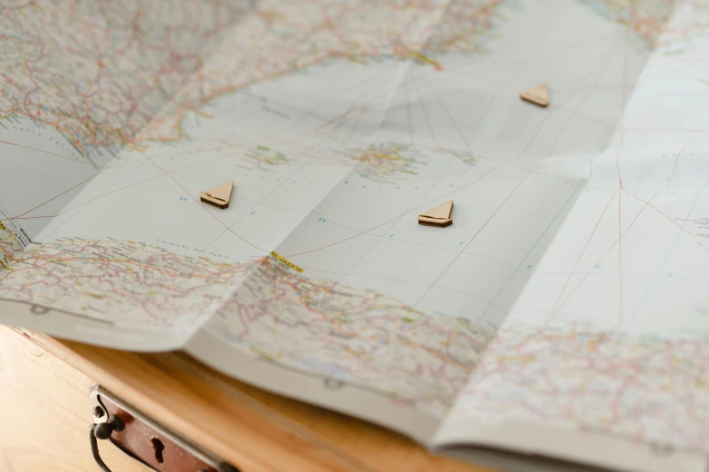 a piece of luggage sitting on top of a wooden table, a jigsaw puzzle, by Jessie Algie, private press, rose gold heart, focus on map, dezeen, close up shot from the side