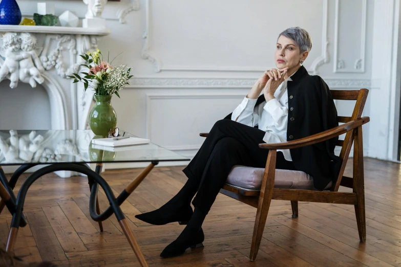 a woman sitting in a chair in a room, a portrait, inspired by Marie-Gabrielle Capet, pexels, figuration libre, short grey hair, on a white table, androgynous person, architectural digest photo