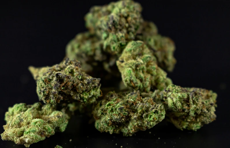 a pile of marijuana buds on a black surface, by Arnie Swekel, unsplash, fantastic realism, side view close up of a gaunt, high quality product image”, nugget, lush greens