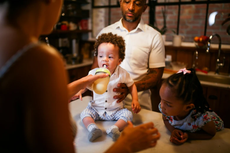 a group of people in a kitchen with a baby, a portrait, pexels, fan favorite, ( ( dark skin ) ), drink, toddler