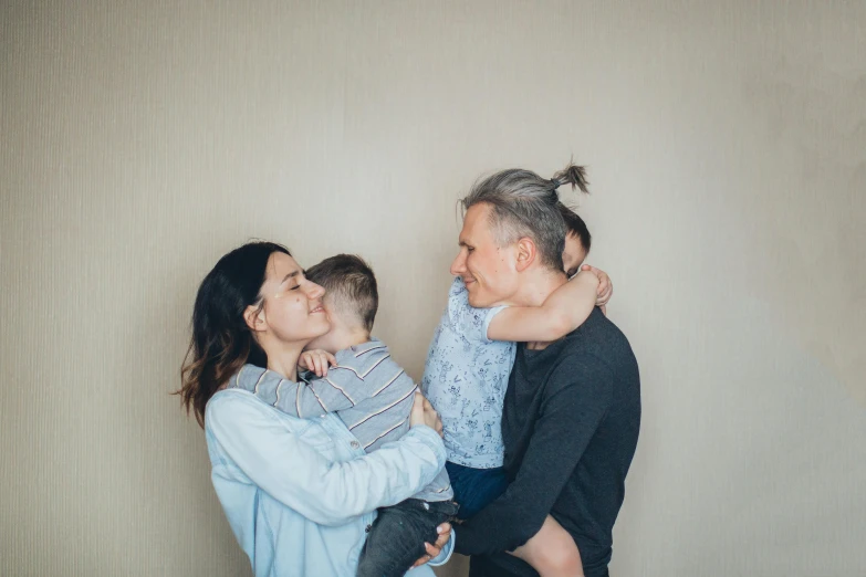 a woman holding a baby while standing next to a man, pexels contest winner, incoherents, grey hair, hugging each other, pictures of family on wall, profile image