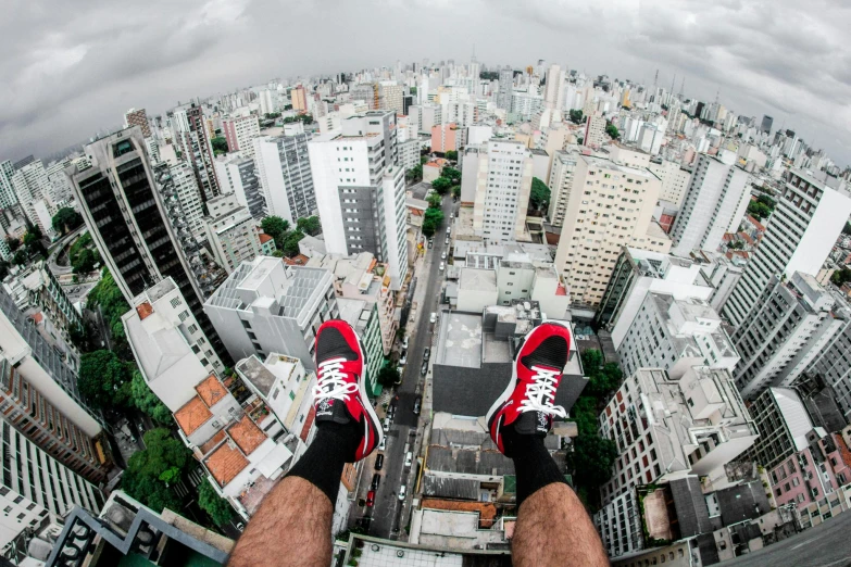 a man standing on top of a tall building, by Joze Ciuha, pexels contest winner, hyperrealism, sneakers, go pro footage, red shoes, icaro carvalho