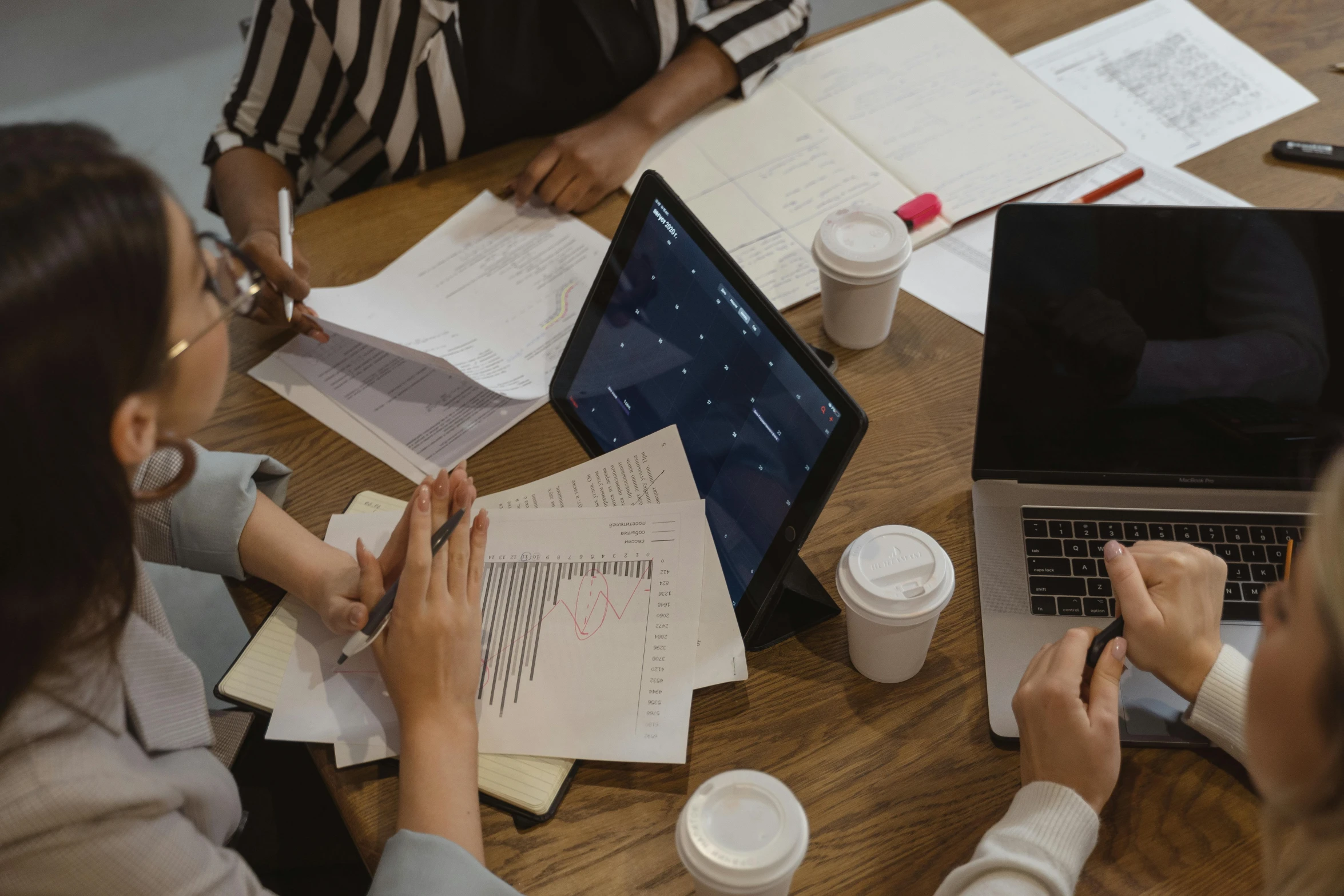 a group of people sitting around a table with laptops, pexels contest winner, analytical art, holding notebook, background image, close - up photograph, aida muluneh