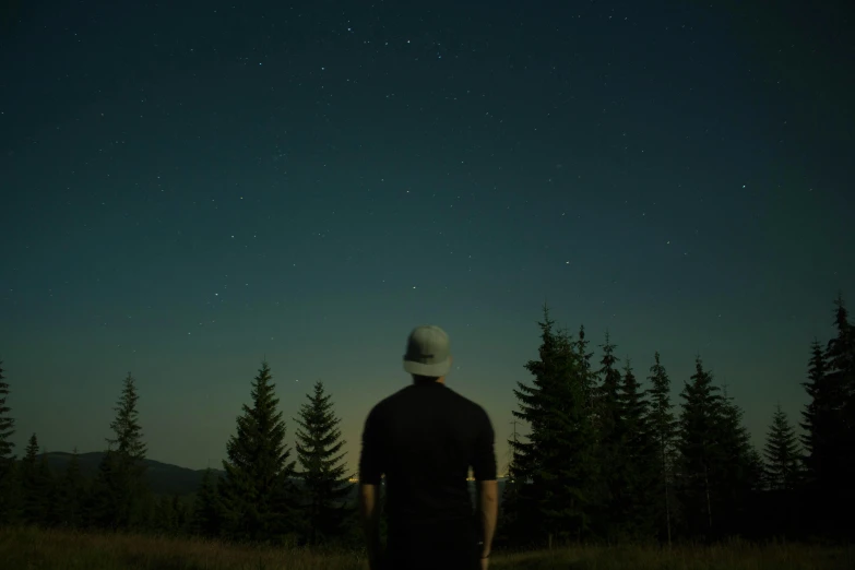 a man standing on top of a grass covered field, an album cover, by Attila Meszlenyi, pexels contest winner, magical realism, looking at the stars, in the woods at night, slightly minimal, lo fi