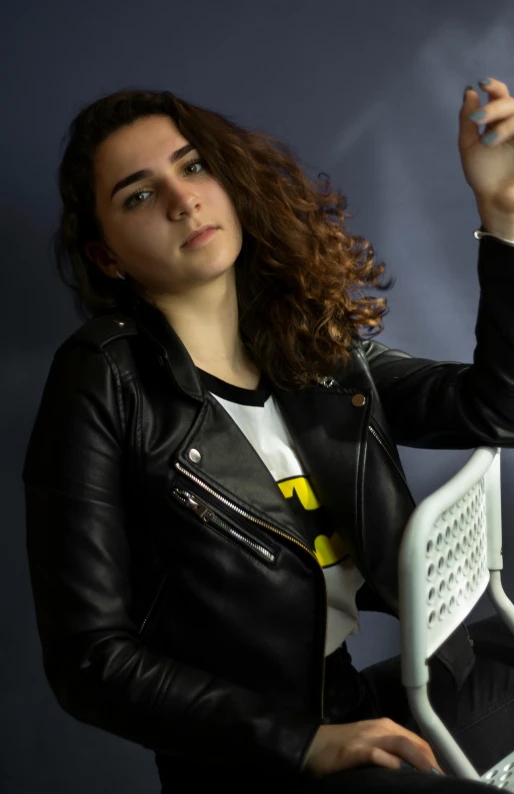 a woman sitting in front of a laptop computer, an album cover, inspired by Ion Andreescu, pexels, photorealism, wearing a black leather jacket, curls, hero pose, ((portrait))