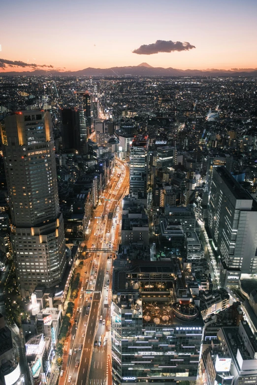 an aerial view of a city at night, a picture, inspired by Kanō Naizen, unsplash contest winner, tall buildings on the sides, arasaka, fujifilm”, city street at dusk