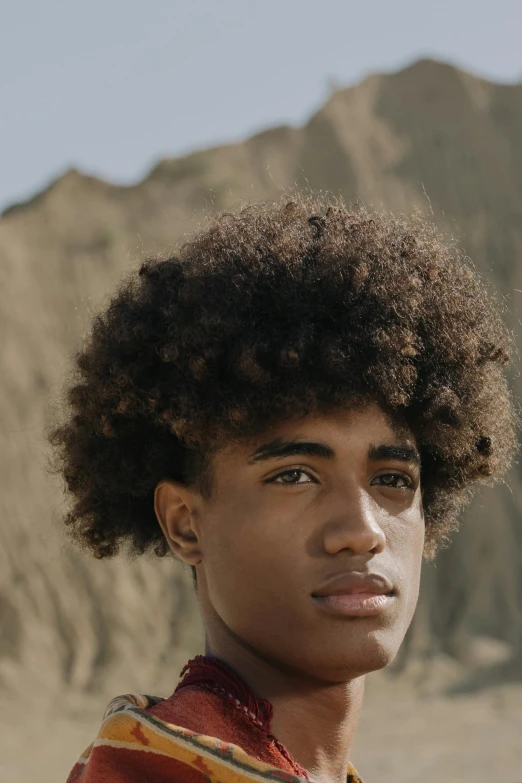 a young man standing in front of a mountain, by Cosmo Alexander, trending on pexels, renaissance, curls hair, black teenage boy, square masculine facial features, ultra high quality model