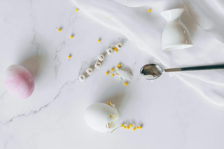 a spoon that is sitting on a table, a still life, inspired by Cerith Wyn Evans, trending on pexels, eggs, white marble, petals falling, white and yellow scheme