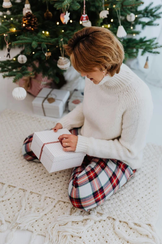 a little girl sitting on the floor in front of a christmas tree, wearing a white sweater, woman, profile image, flannel