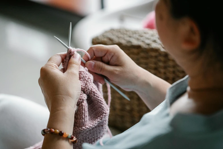 a woman sitting on a couch holding a pair of scissors, a cross stitch, trending on pexels, knitted hat, avatar image, sculpting, playing