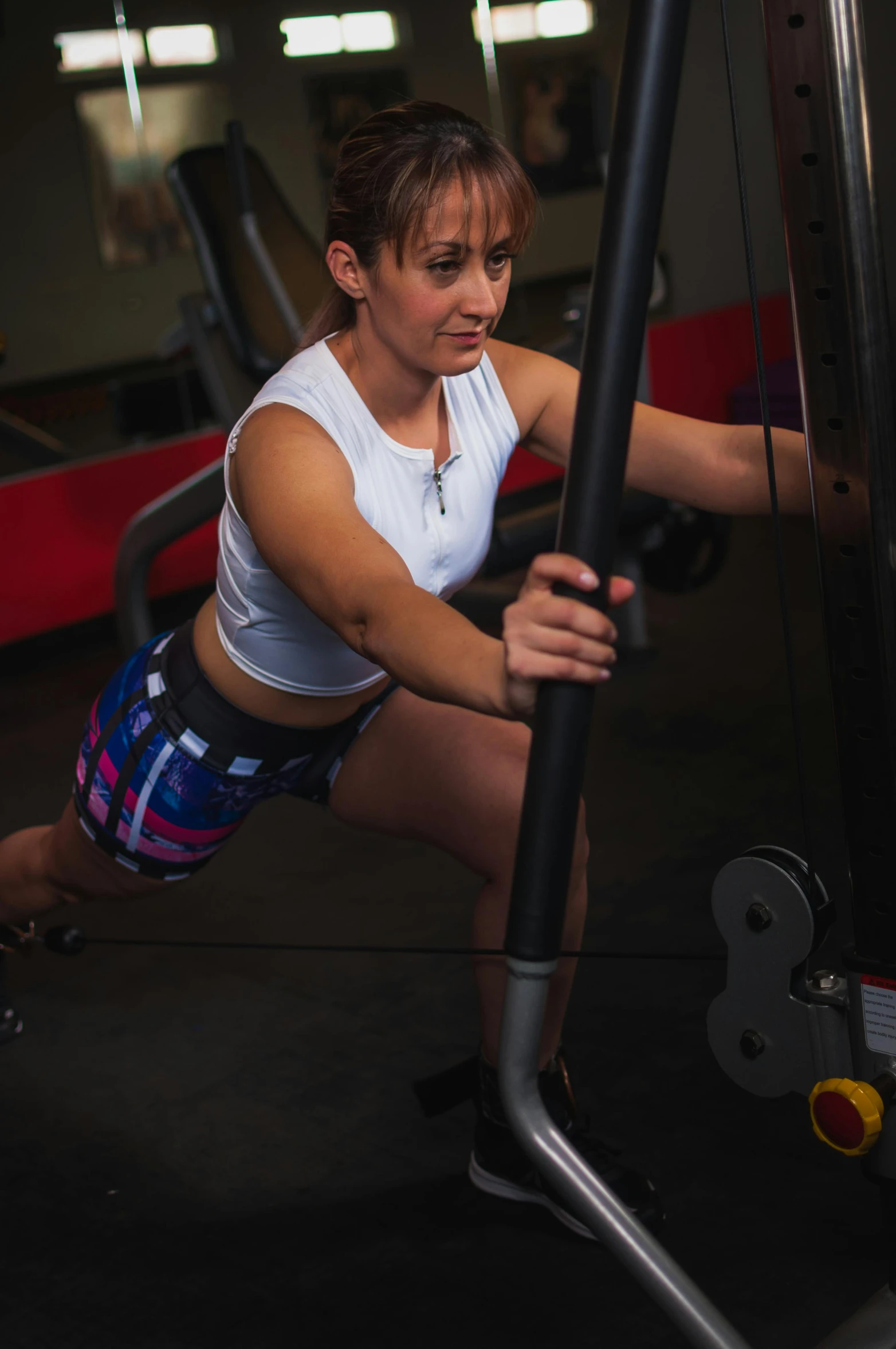 a woman working out on a machine in a gym, a portrait, by Natasha Tan, jaime jasso, focused photo, crouching, “ iron bark