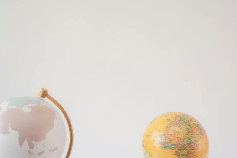 a close up of a globe on a table, on a pale background, background image, two still figures facing camera, schools