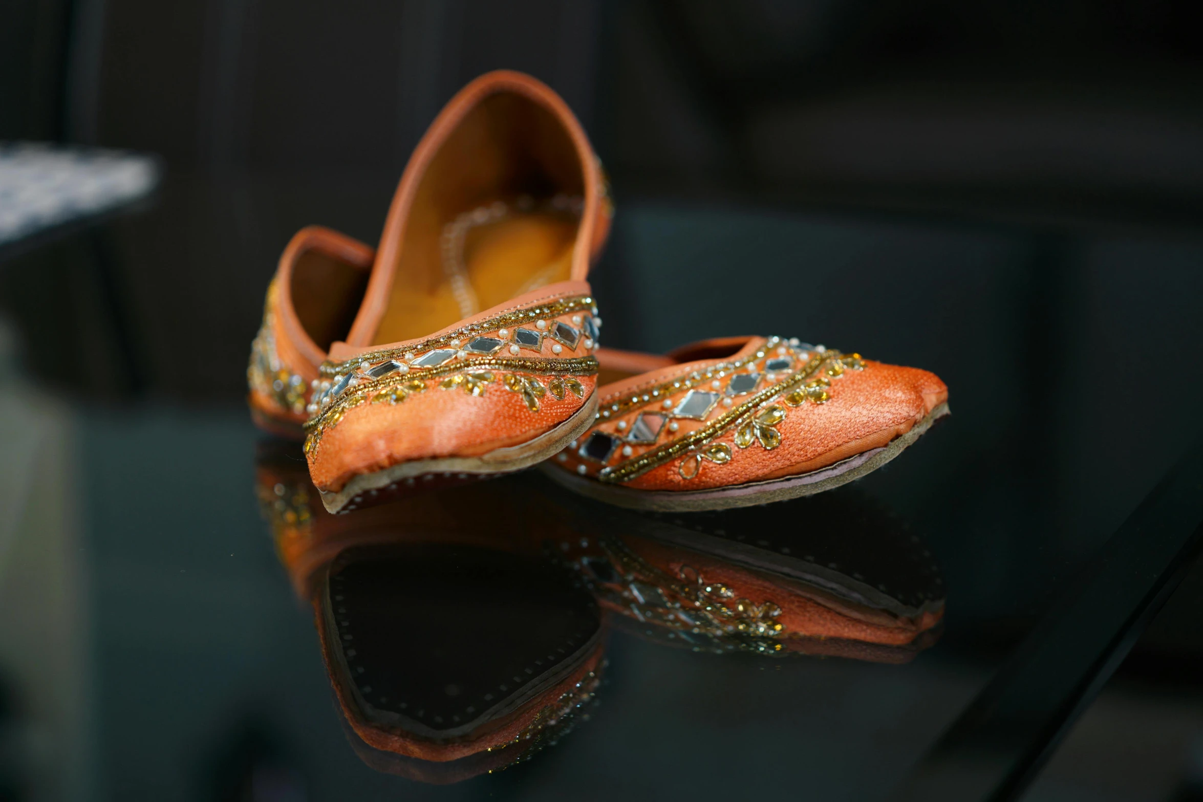 a pair of shoes sitting on top of a glass table, hindu ornaments, orange hue, shot on sony alpha dslr-a300, brown